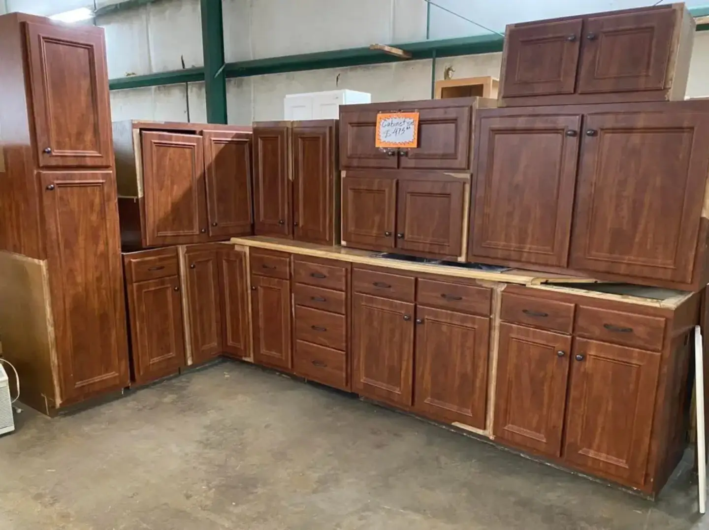 Complete set of cherry wood kitchen cabinets including tall pantry units, wall cabinets, and base drawers for kitchen remodeling at Re-Store Warehouse