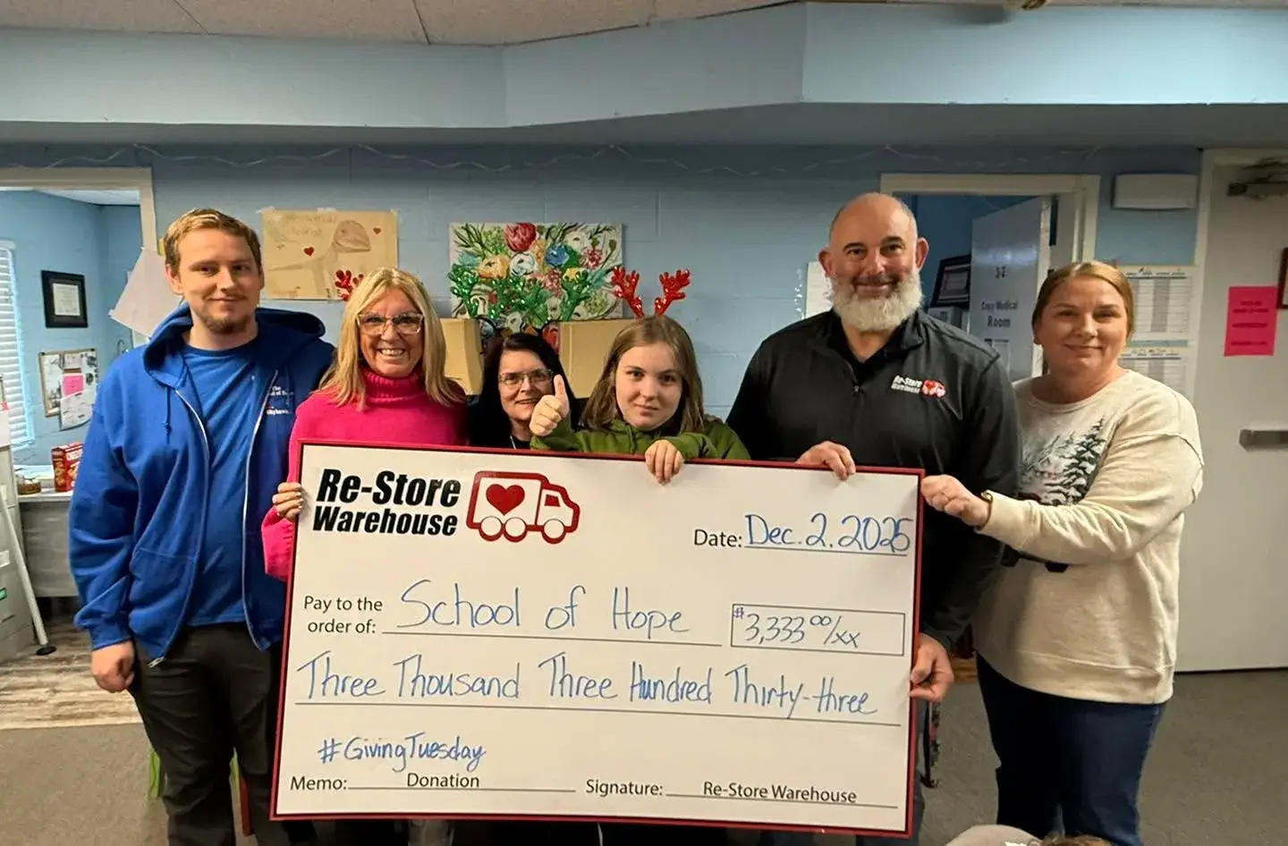 Members of the Re-Store Warehouse team presenting a large oversized donation check for $3,333 to representatives of School of Hope for Giving Tuesday.