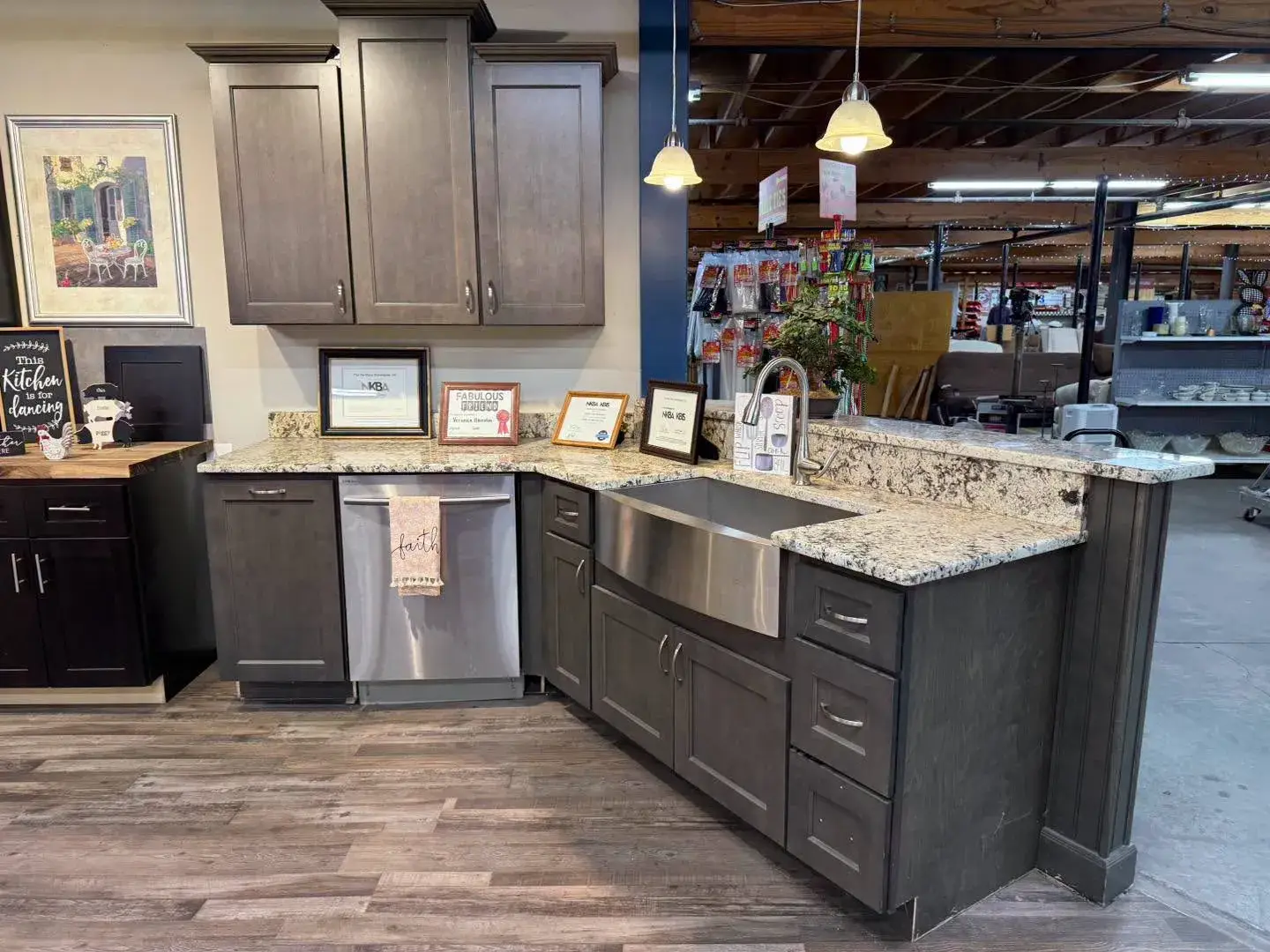 Modern dark grey kitchen cabinets with granite countertops, a stainless steel apron apron-front sink, and a built-in dishwasher on display inside Re-Store Warehouse.
