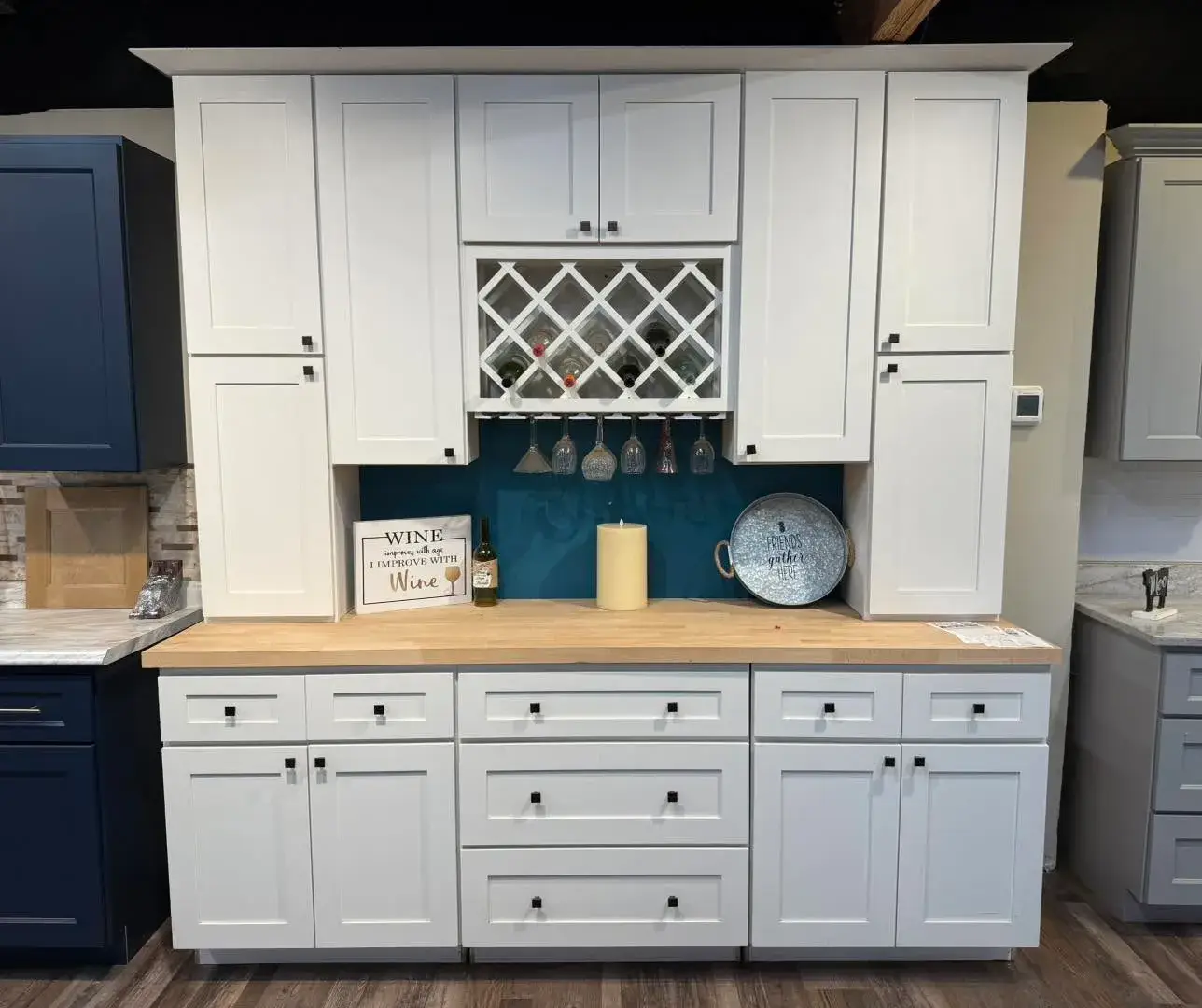 A custom white shaker-style kitchen buffet and wall unit featuring a butcher block countertop, integrated wine rack, stemware holder, and black hardware.